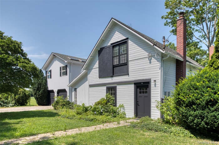 View of front of property featuring a chimney, a front yard, driveway, and a garage