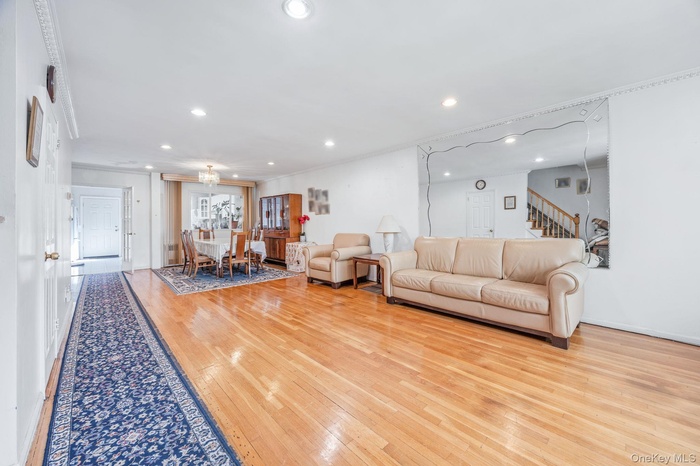 Living room featuring light wood-style floors, recessed lighting, stairs, and crown molding