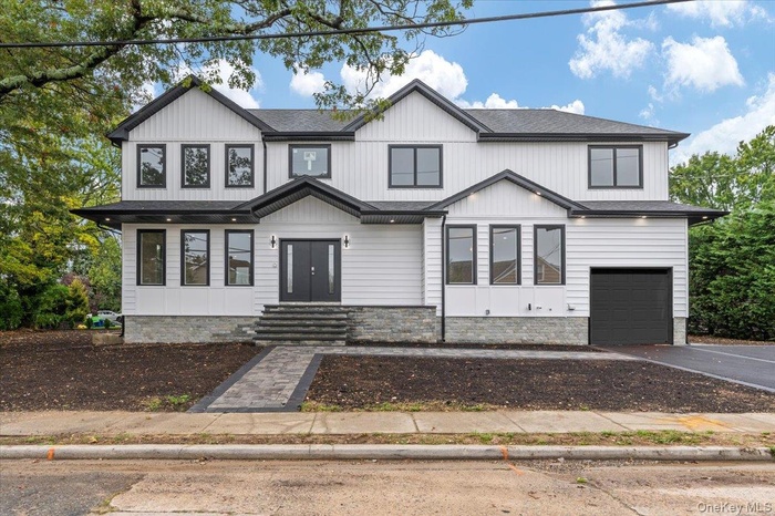 Modern farmhouse with an attached garage, asphalt driveway, and roof with shingles