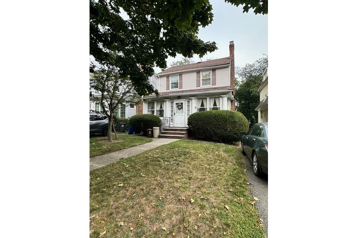 View of front of property with a chimney, a front lawn, and brick siding