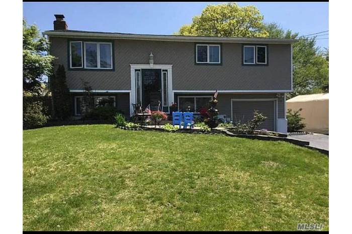 View of front of property featuring a chimney, driveway, a front yard, and an attached garage