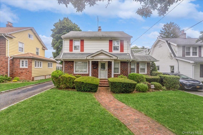 View of front facade featuring brick siding, a front lawn, and a chimney