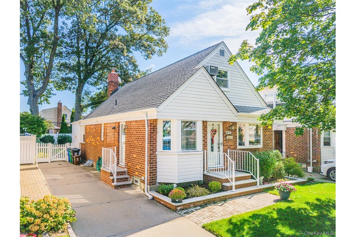 View of front of house with roof with shingles, brick siding, and a chimney