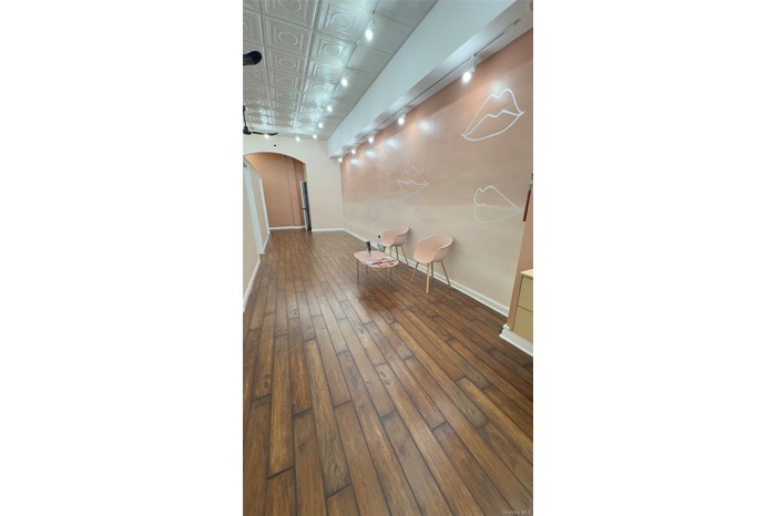 Unfurnished room with rail lighting, arched walkways, dark wood-style flooring, and an ornate ceiling