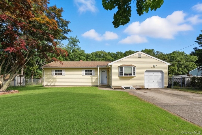 Ranch-style house featuring driveway, an attached garage, and a storage unit