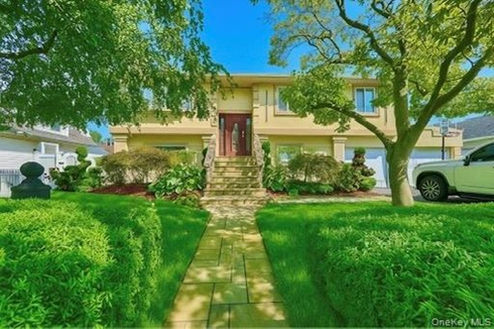 Raised ranch featuring a front lawn and stucco siding