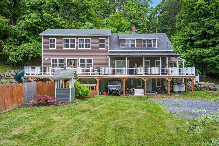 View of front facade featuring a chimney, a wooden deck, and driveway