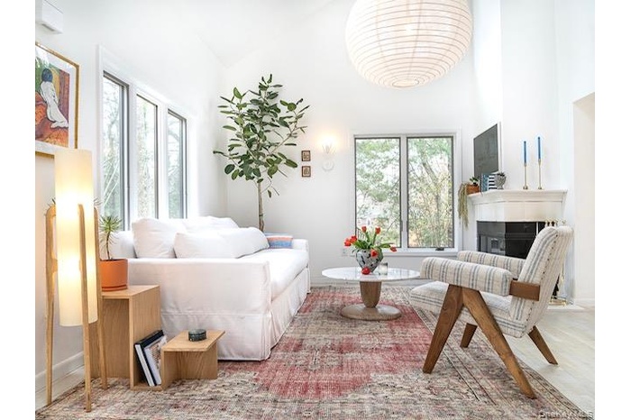 Living room featuring a towering ceiling, a glass covered fireplace, and wood finished floors