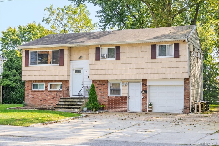 Bi-level home featuring brick siding, driveway, and a garage