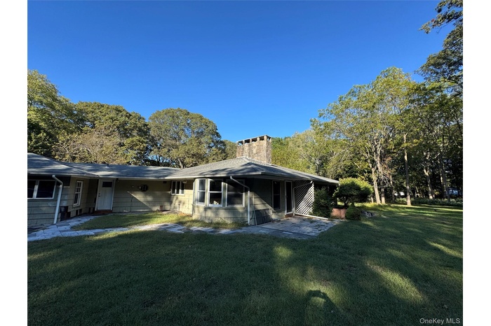 View of property exterior featuring a lawn and a chimney