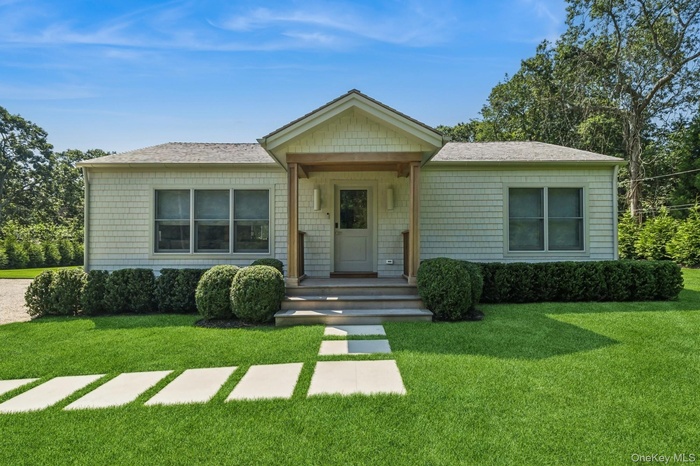 View of front of property featuring a front lawn, covered porch, and roof with shingles
