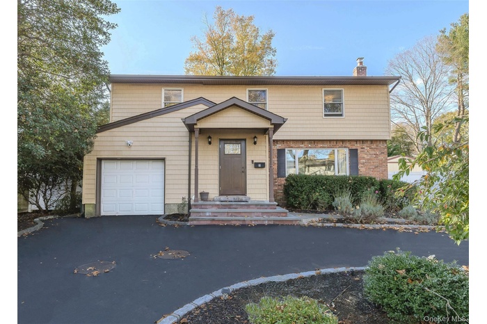 View of front of house featuring a chimney, asphalt driveway, and a garage