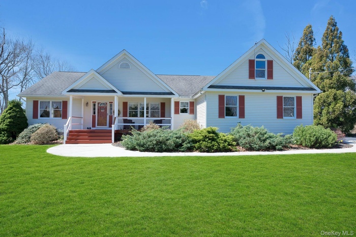 View of front of home featuring covered porch, a front yard, and a shingled roof