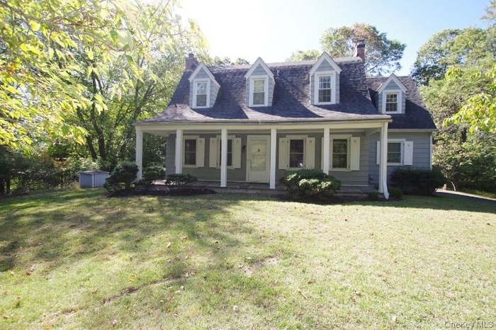 Colonial house with a chimney, a porch, and a front lawn