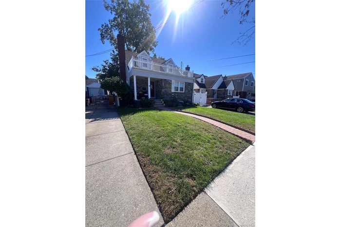 View of front of home featuring a chimney, a gate, stone siding, and covered porch
