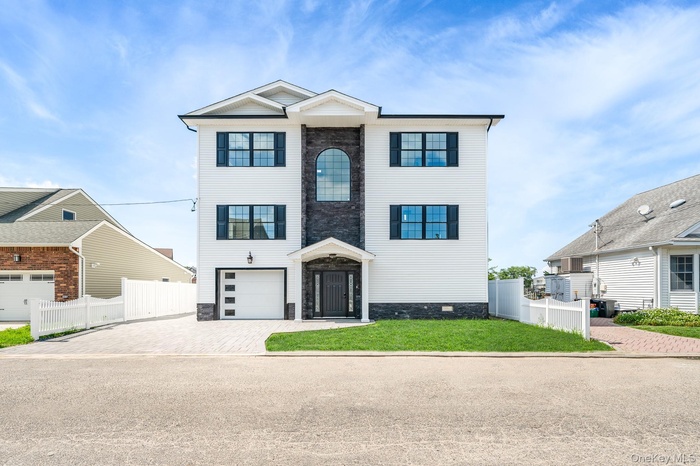 View of front of house featuring decorative driveway, stone siding, and an attached garage