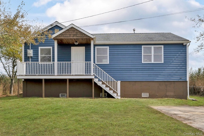 View of front of property with a front lawn, a shingled roof, crawl space, and stairs