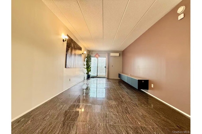 Spare room with a textured ceiling and an AC wall unit