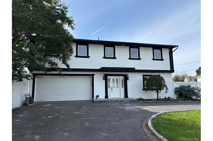 View of front of home featuring stucco siding, asphalt driveway, and a garage