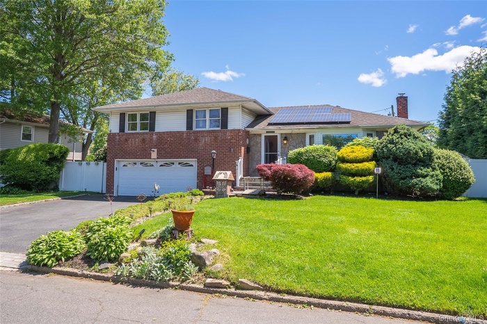 Front of the house with driveway, solar panels, , 2 car garage, and a chimney
