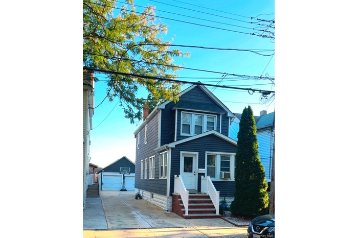 View of front facade with a chimney, an outdoor structure, and a garage