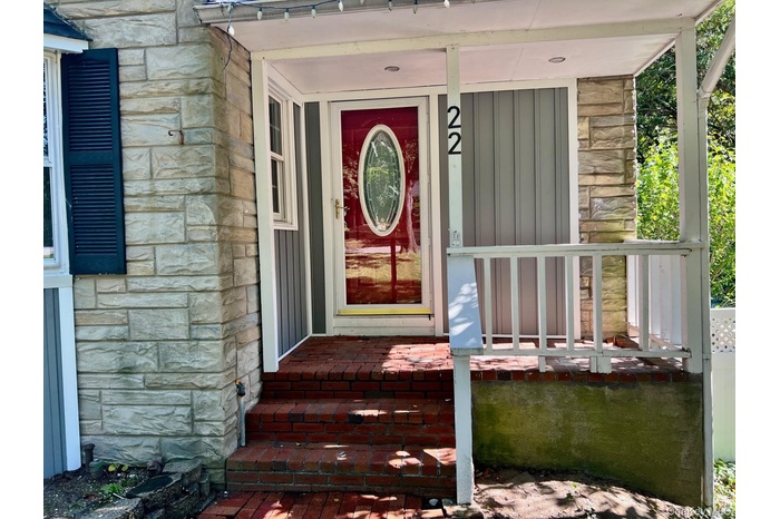 View of exterior entry with stone siding, covered porch, and board and batten siding