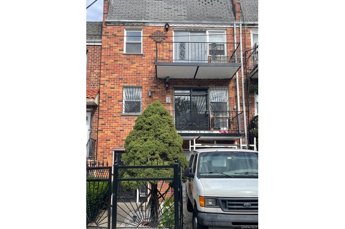 View of front of home featuring a balcony, brick siding, and a shingled roof