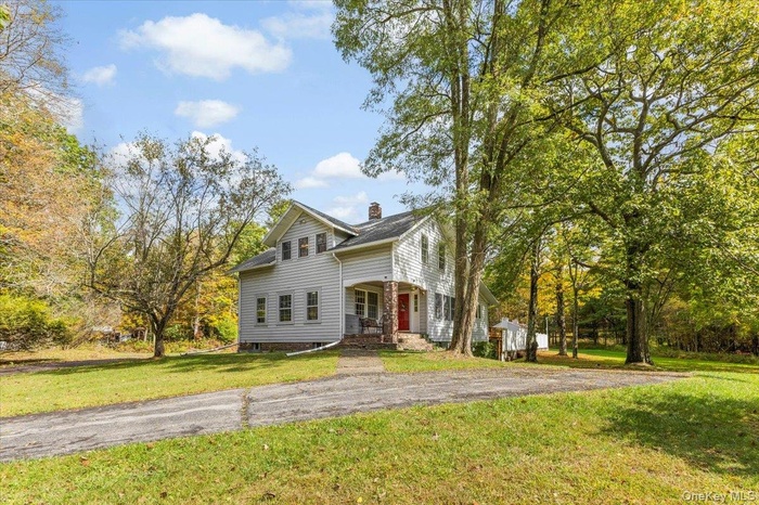 View of front of home with a front lawn, a porch, and a chimney