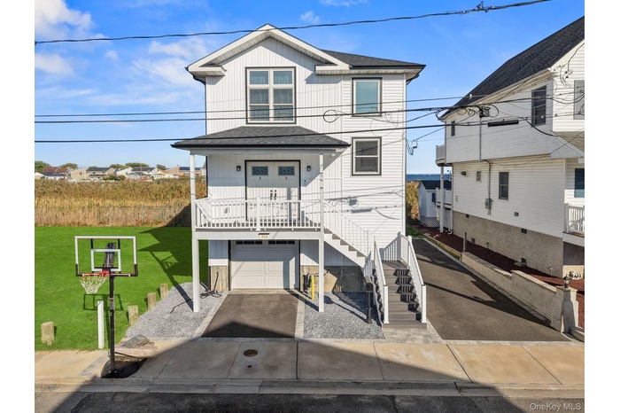 View of front of property with stairs, a garage, and covered porch