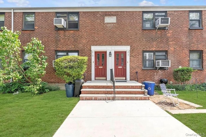 Doorway to property with a lawn, brick siding, and cooling unit