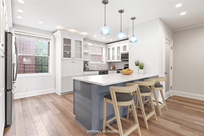 Kitchen featuring white cabinets, glass insert cabinets, a kitchen breakfast bar, pendant lighting, and recessed lighting