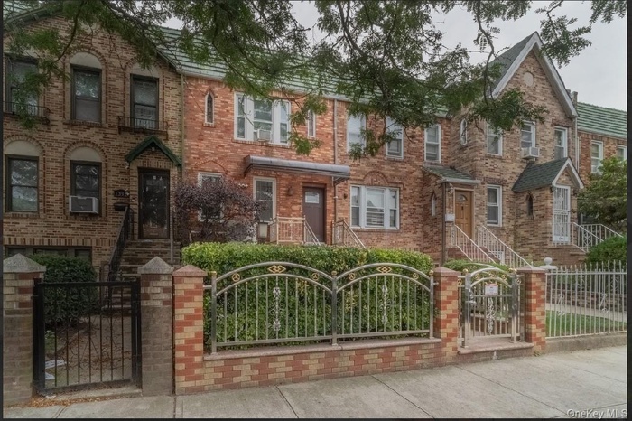 View of front of home with a gate, a fenced front yard, and brick siding