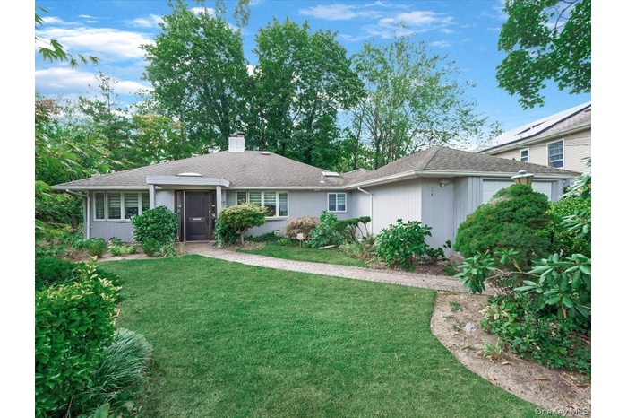 Single story home featuring roof with shingles, a front yard, and a chimney