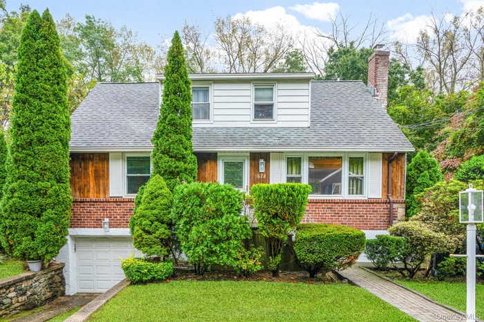 Cape Cod featuring roof with shingles, a front yard, and brick siding