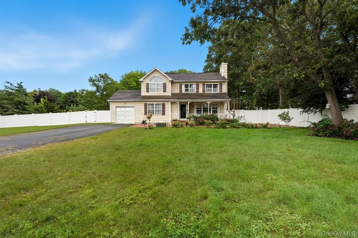 View of front of house with covered porch, driveway, a chimney, and view of scattered trees