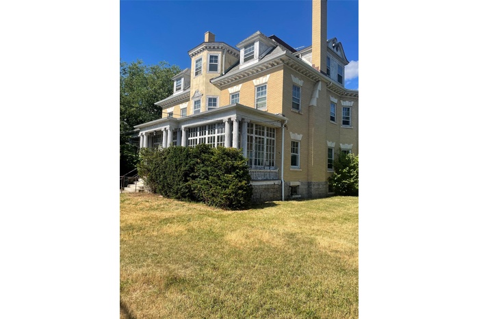 Back of house with a chimney, brick siding, and a lawn