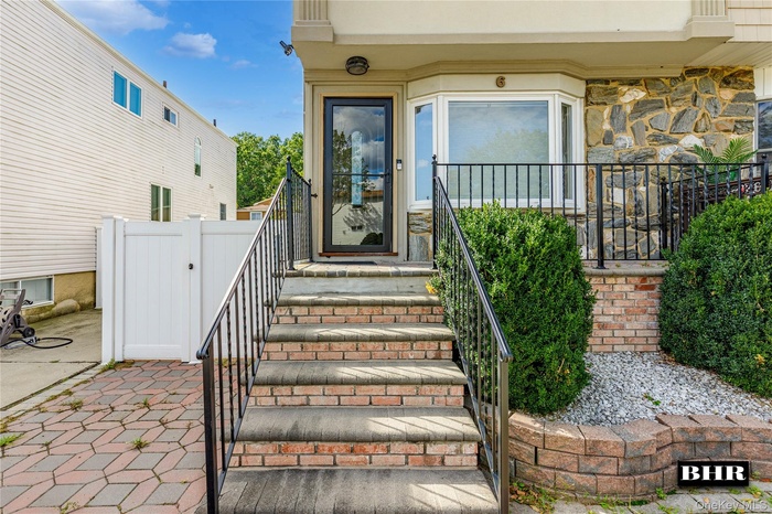 Entrance to property featuring a gate, a patio area, stone siding, and stucco siding