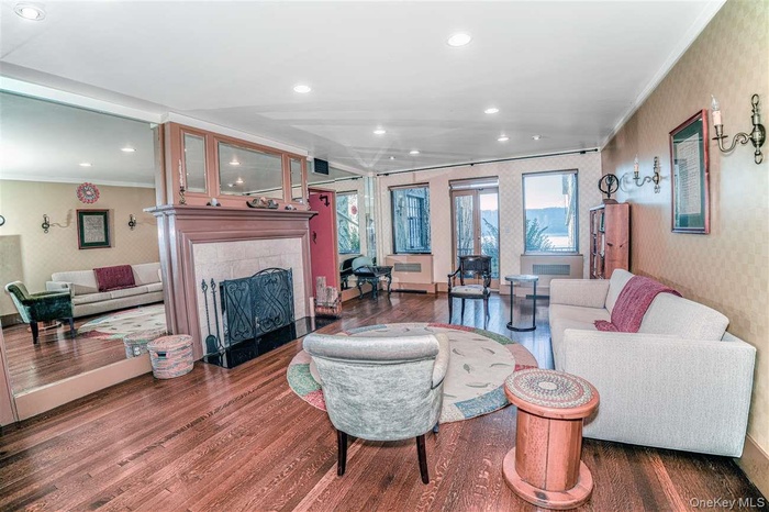 Living room featuring wallpapered walls, crown molding, a tile fireplace, dark wood-type flooring, and recessed lighting