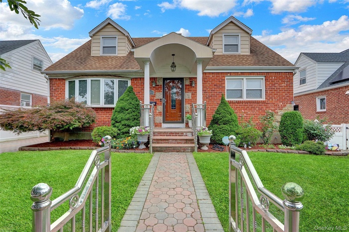 View of front of home with brick siding, roof with shingles, and a front lawn