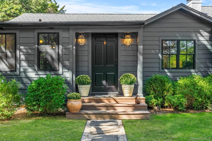 Doorway to property featuring a shingled roof and a yard