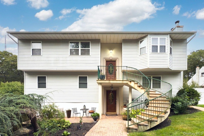 Bi-level home with stairs, a chimney, and a balcony