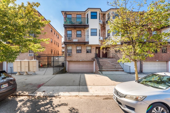 Townhome / multi-family property featuring brick siding, concrete driveway, an attached garage, stairs, and a balcony