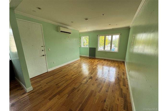 Unfurnished living room featuring crown molding, dark wood-type flooring, an AC wall unit, and recessed lighting