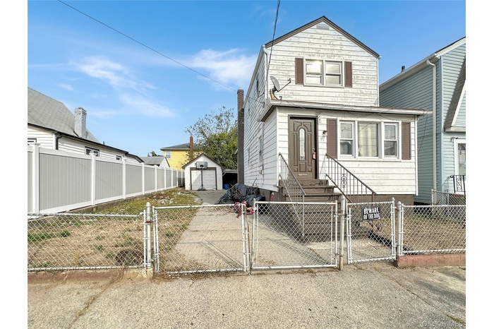 View of front facade featuring a gate, a fenced front yard, and an outdoor structure