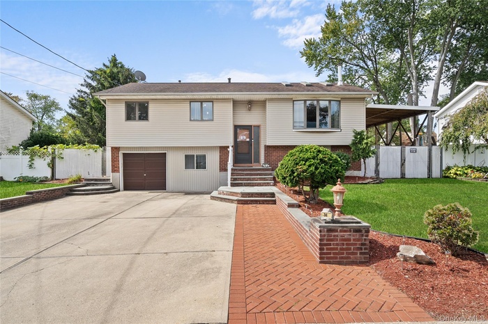 Raised ranch featuring driveway, a garage, and brick siding