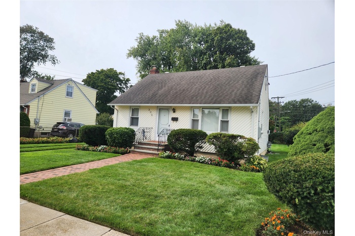 View of front of property featuring a front yard, a chimney, and a shingled roof