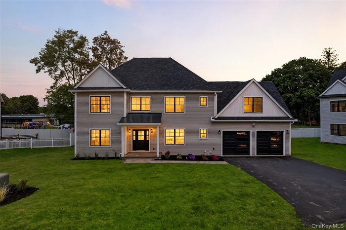 Modern farmhouse with asphalt driveway, a garage, and roof with shingles