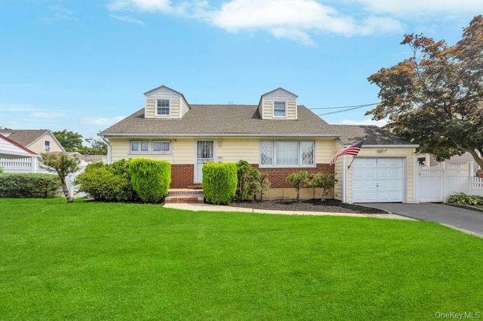 Cape cod-style house with brick siding, asphalt driveway, a garage, and a shingled roof