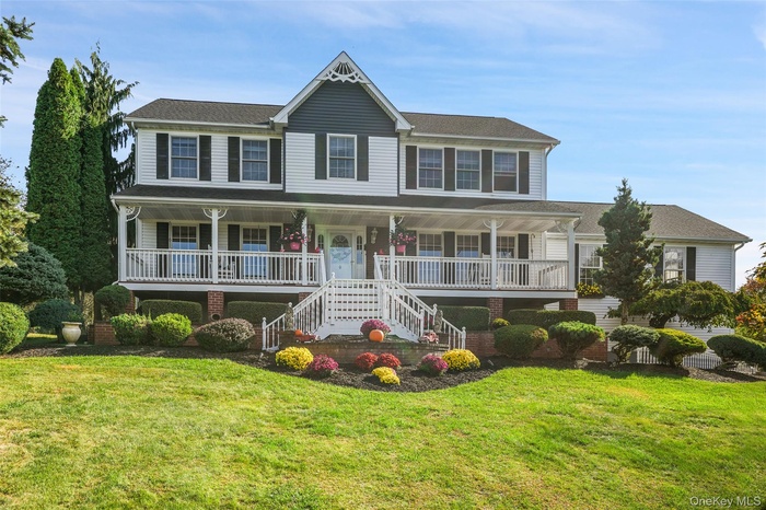 View of front facade featuring covered porch, stairs, a front yard, and roof with shingles