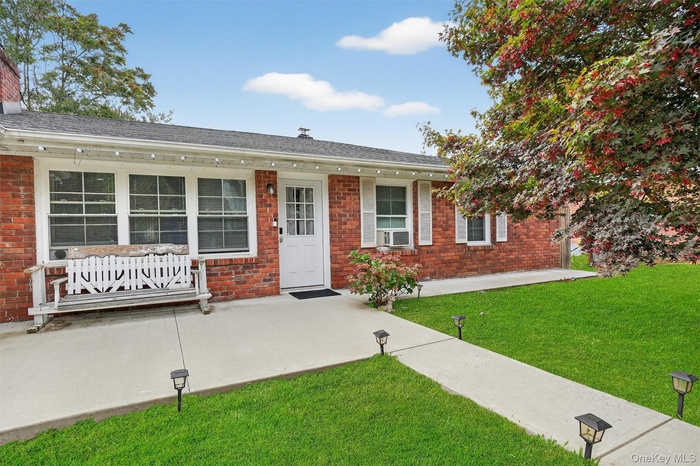 Single story home featuring a patio area, a front yard, and brick siding